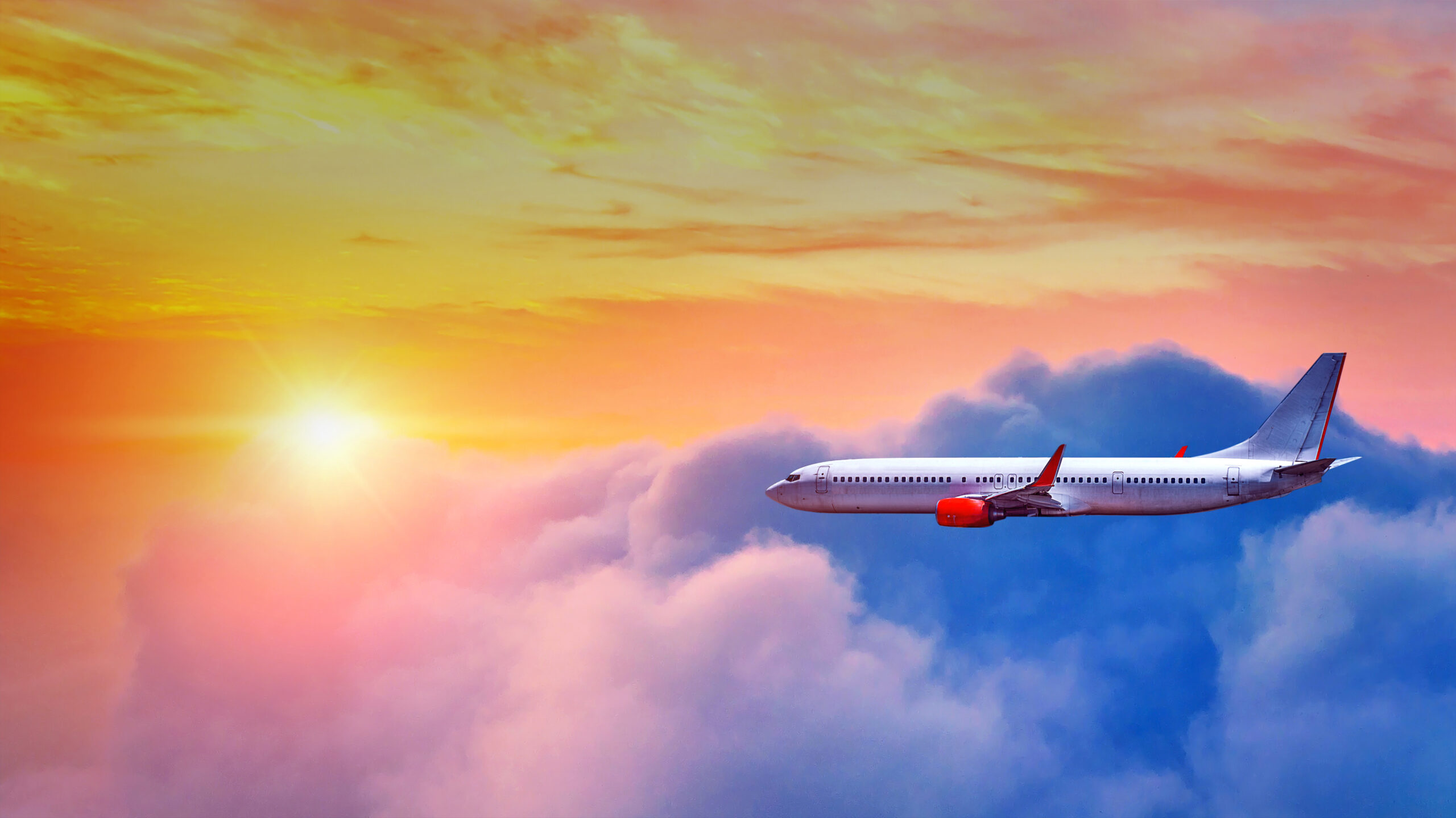 Airplane flying above clouds in sunset light.